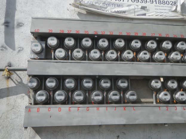 Ein Nahaufnahme eines Elektrizitätszählers an einer Gebäudewand, mit einem Banner mit Text oben auf dem Bild.