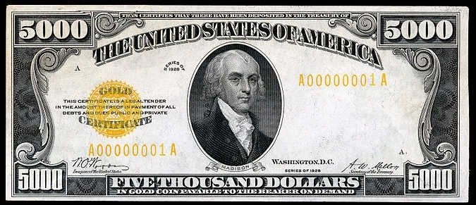 Eine US-amerikanische Fünfausenddollarnote mit einem Porträt von George Washington, auf der "United States" und "Five Thousand Dollars" in fetter Schrift auf einem schwarzen Hintergrund abgedruckt sind.