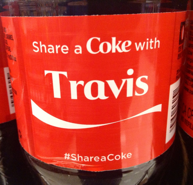 Eine Coca-Cola-Flasche mit der Aufschrift "Share a coke with TRAVIS" darauf gedruckt.