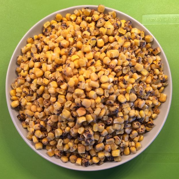 Ein weißer Schüssel mit Maiskörnern steht auf einem grünen Hintergrund mit Text unten.