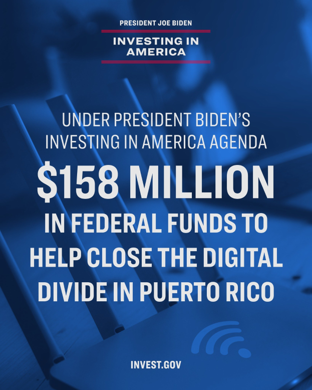 Plakat mit der "berschrift "Unter Pr"sident Bidens Investing in America-Agenda: 158 Millionen Dollar aus Bundesmitteln, um die digitale Kluft in Puerto Rico zu schließen" mit einem Laptop, Papieren und einem Kaffeebecher auf einem Tisch davor.