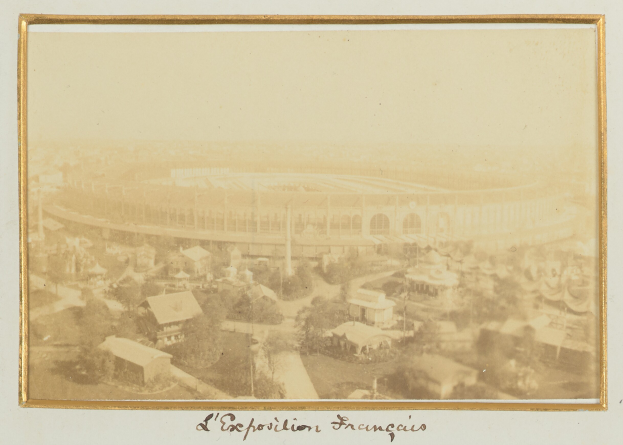 Old black-and-white photo of a stadium surrounded by buildings, trees, and utility poles with text at the bottom.