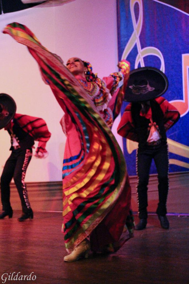 Menschen in Kostümen auf einer Bühne mit einem Vorhang mit einem Bild im Hintergrund.