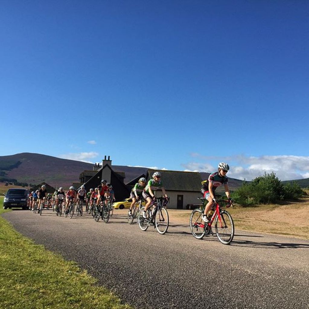 Eine Gruppe von Menschen, die mit dem Himmel im Hintergrund Fahrrad fahren.