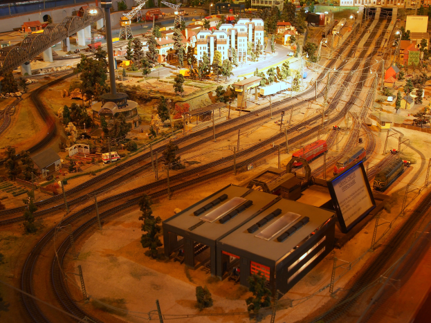Eine Modellbahnanlage in einem Museum mit Miniaturgebäuden, Bäumen, Fahrzeugen und anderen Gegenständen, die eine belebte Stadtkulisse schaffen.