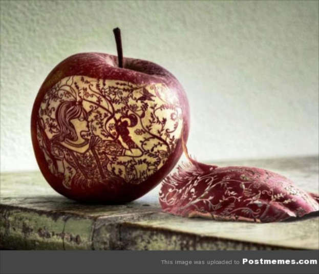 Ein Nahaufnahme eines Apfels mit einem Design auf seiner Oberfläche, das auf einer Plattform liegt, mit einer Wand im Hintergrund und Text am unteren Rand des Bildes.