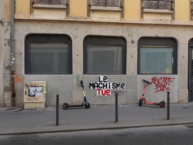 Zwei Roller auf einer Straße neben einem Gebäude mit Fenstern, Geländern und einem Rohr geparkt.