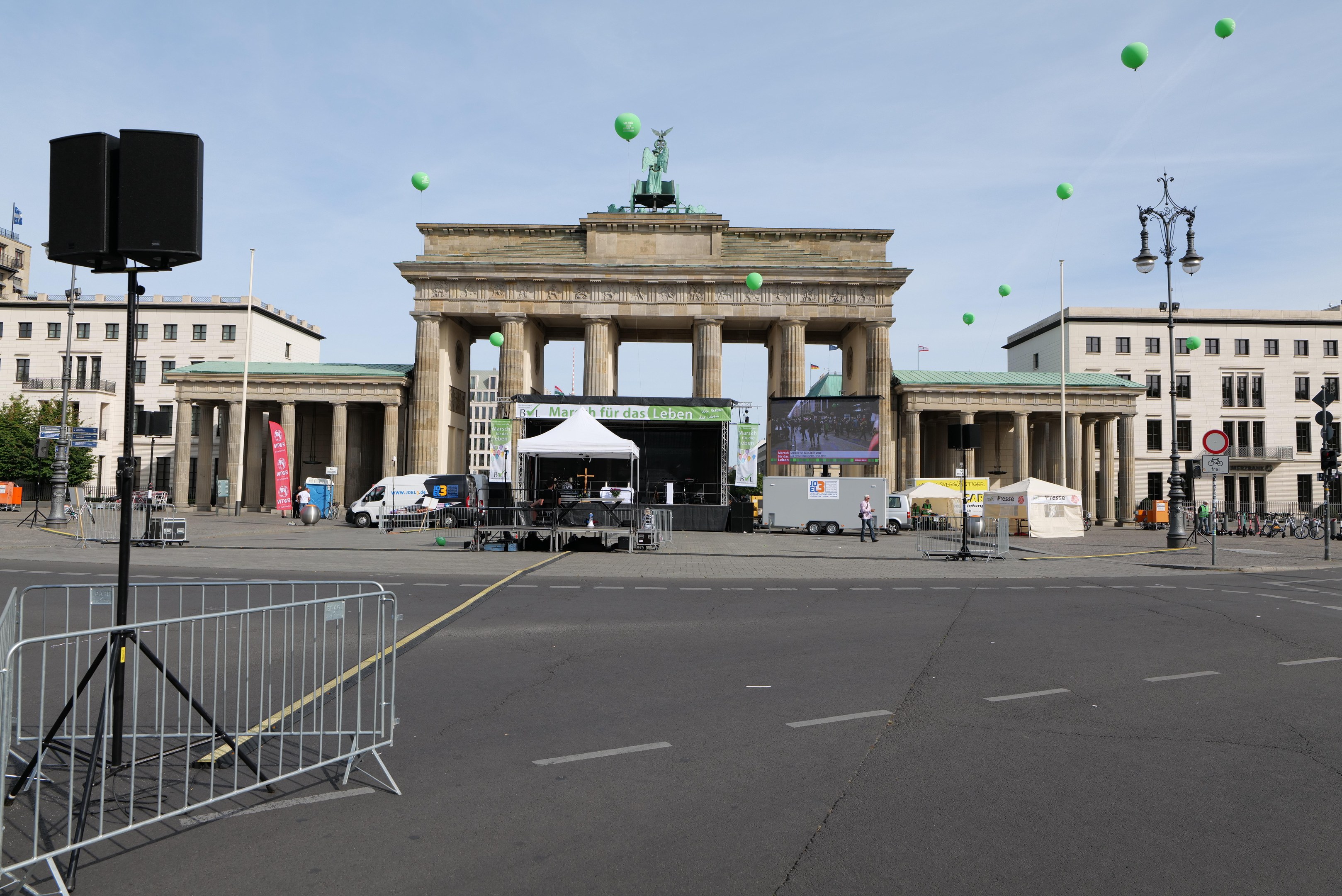 Das Brandenburgische Tor in Berlin, Deutschland, mit seinen klassischen Säulen und der Quadriga-Statue, umgeben von urbanen Elementen und festlichen grünen Luftballons während des Berlin-Marathons.