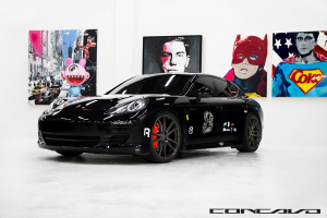 Ein schwarzer Nissan-Sportwagen ist vor Cartoon-Postern geparkt, mit einer kleinen Inschrift am unteren Rand des Bildes.