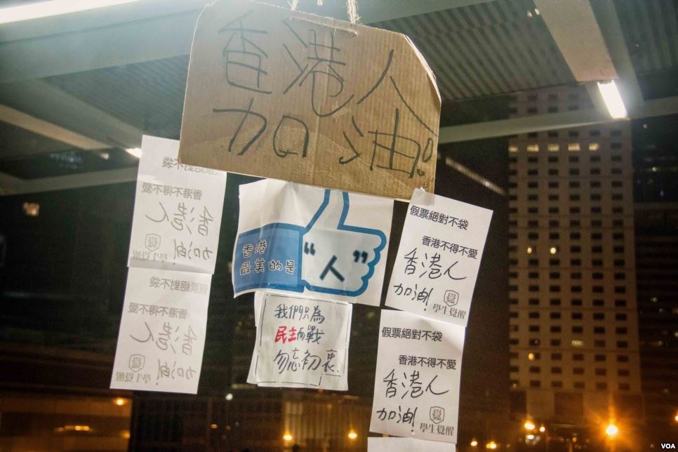 Menschen mit Protestschildern vor einem beleuchteten Gebäude bei Nacht.