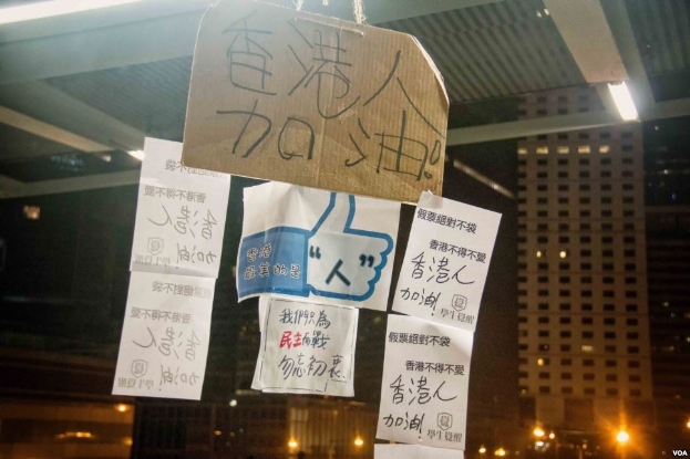 Menschen mit Protestschildern vor einem beleuchteten Gebäude bei Nacht.