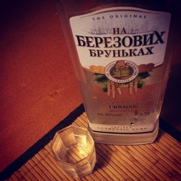 Ein klares Glas mit einer goldenen Flüssigkeit, das auf einer beigen Matte steht.