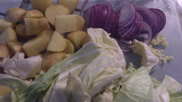 Ein Nahaufnahme-Bild von Zwiebeln, Kartoffeln und Kohl, die zusammen angeordnet sind.