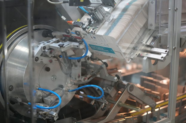 Ein automatisiertes Verpackungssystem auf einem Tisch in einer Fabrik, mit unscharfen Objekten im Hintergrund.