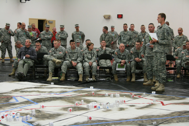 Eine Gruppe von Menschen in der Nähe eines Ausgangsschildes an einer Wand, eine Tür und eine Karte auf dem Boden.